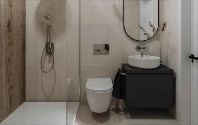 This image shows the bathroom. It has a toilet with a standing shower on the left and a sink with a mirror the on the right. The wall to the shower is made of wood, whilst the rest is marble. The shower has a glass panel seperating it from the rest of the bathroom.