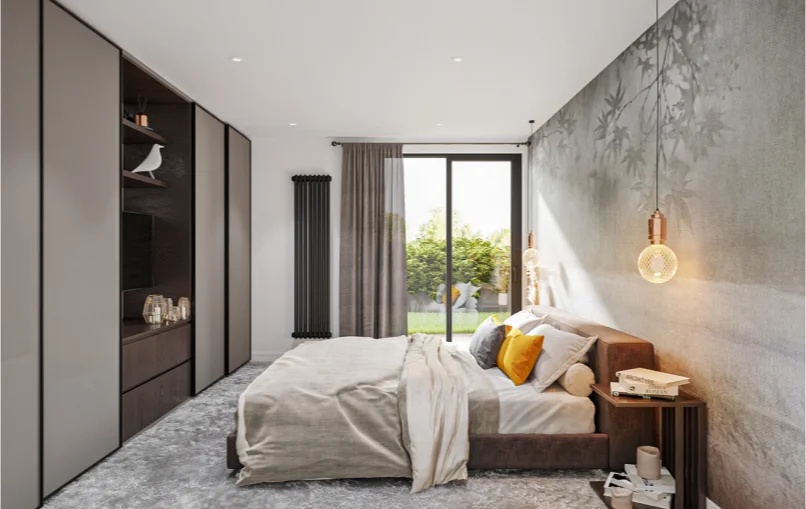 This image shows the bedroom to the apartment. Opposite the double bed is a tv with shelves above it. The room is decorated in a modern style with a gray carpet and two lights hanging from either side of the bed.