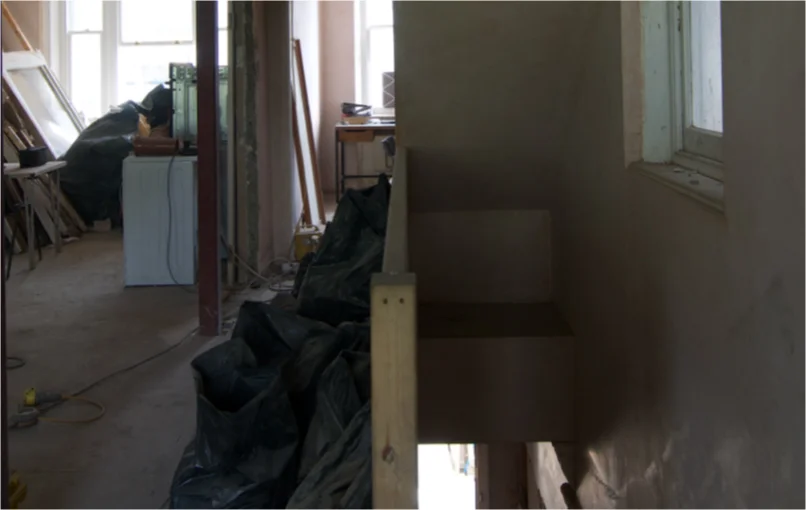 This image depicts the plastered stairwell on the right hand side and the open plan room on the left side.