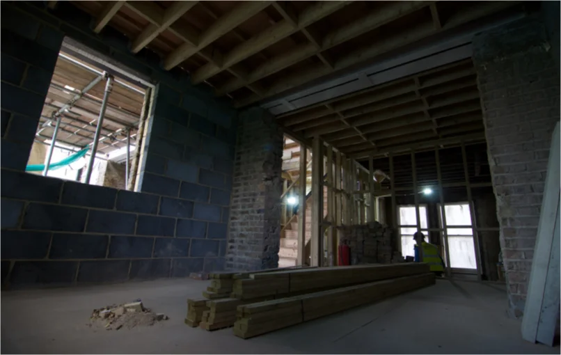 This image depicts a empty room exposing its masonry work as well as open ceilings.